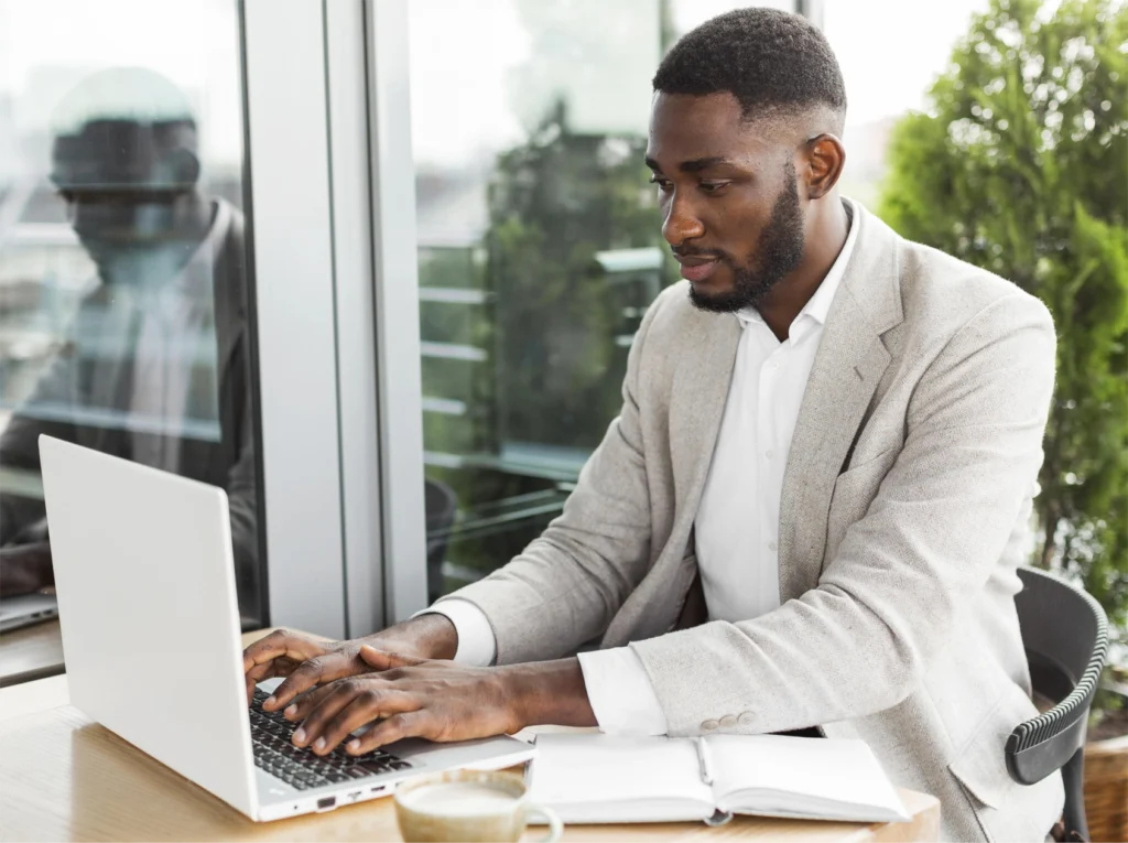 Smiling businessman in a suit sitting at desk working on a laptop