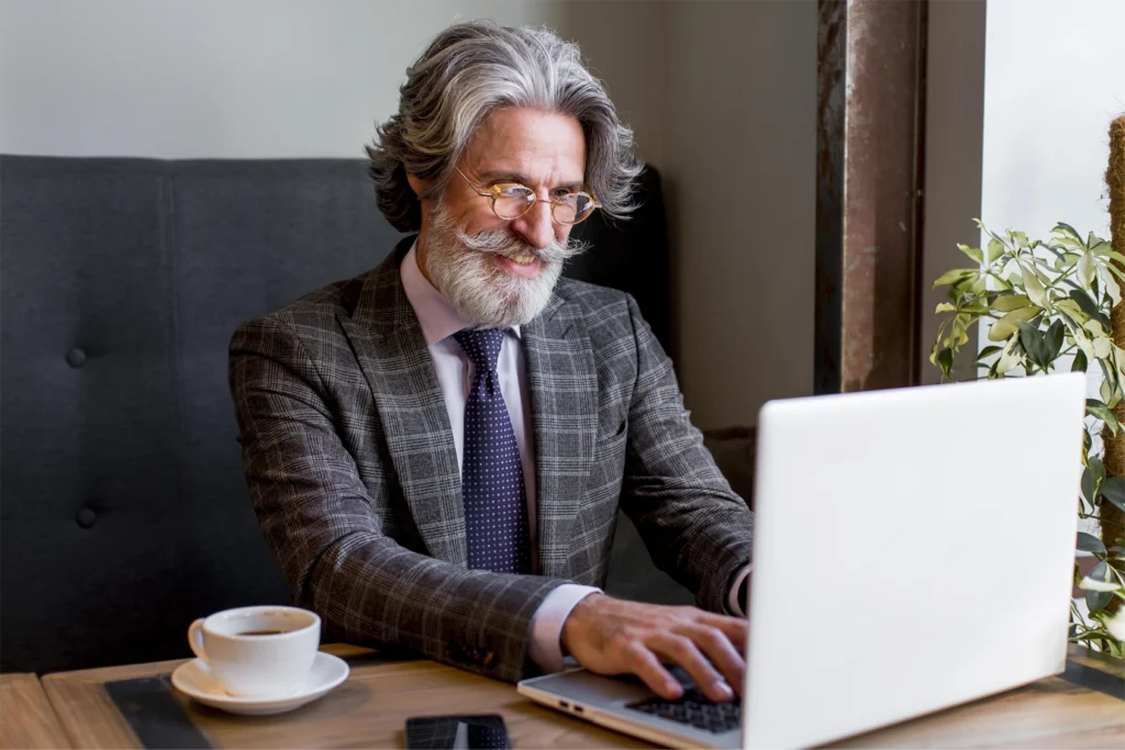 A confident smiling businessman sitting at a laptop