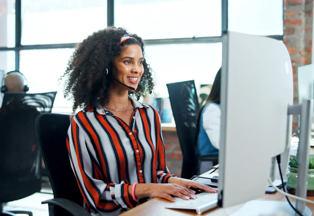 Smiling woman wearing a headset sitting at a computer