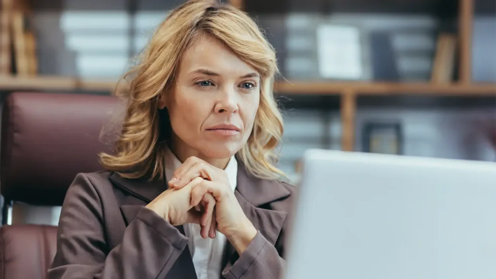 a photo of a stern looking business woman sitting in front of a computer, representing how globalmeet can help Human Resources teams execute their change management communications